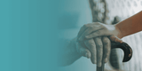 Close-up of hands holding a walking stick with a blurred background

