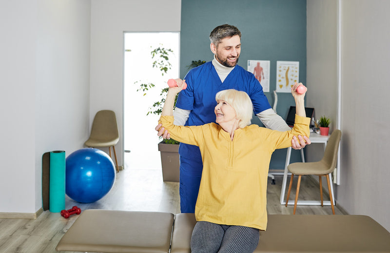 Physiotherapist assisting an elderly patient with exercises in a clinic setting

