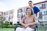 Woman in a wheelchair with a caregiver in an outdoor setting

