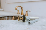 Gold faucet and sink with a plumbing valve on a marble countertop

