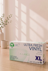 Box of Ultra Fresh Vinyl disposable examination gloves on a wooden surface with a light background

