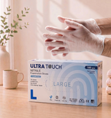 Box of Ultra Touch nitrile examination gloves with a person wearing a glove on a table.

